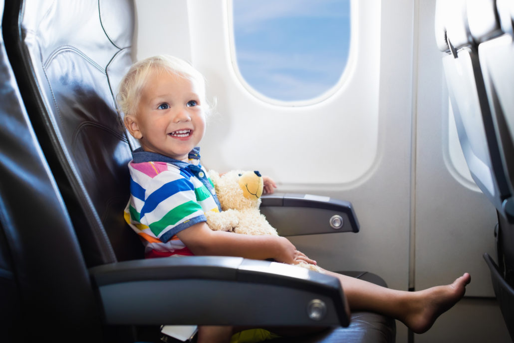 toddler on plane in seat with teddy bear