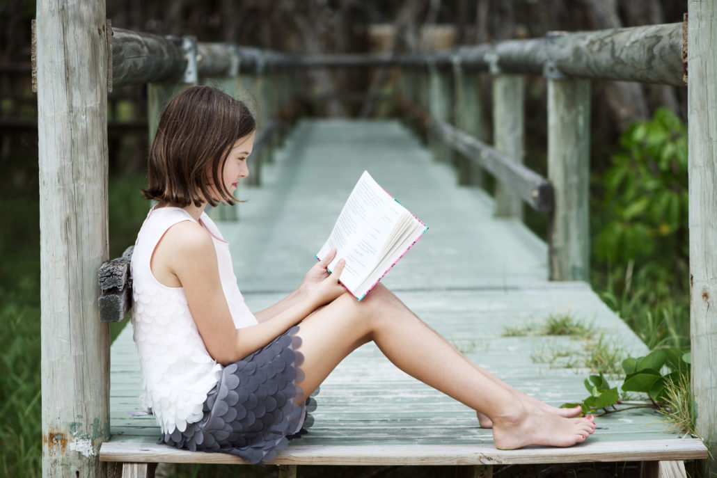 Girl reading on dock by water