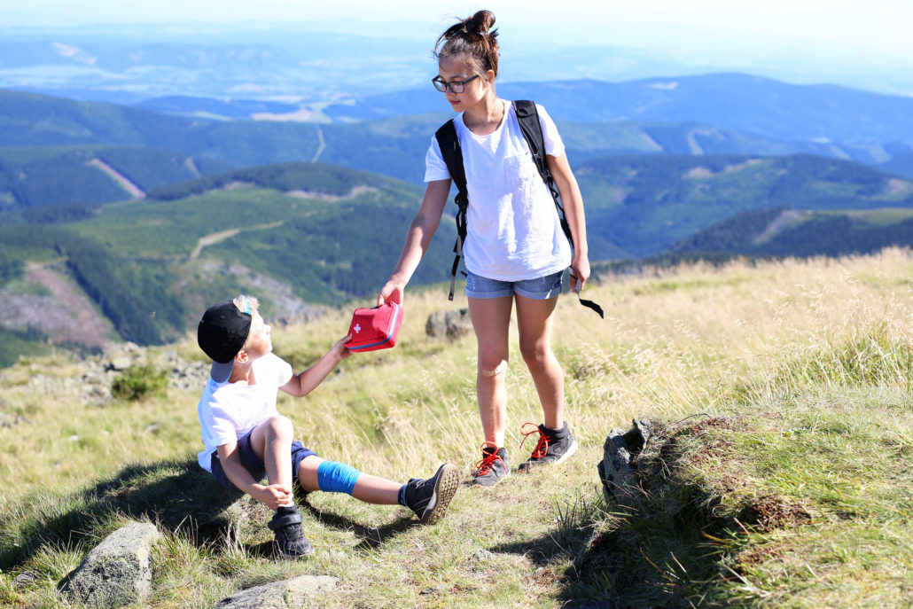 sister gives brother first-aid kit on hike