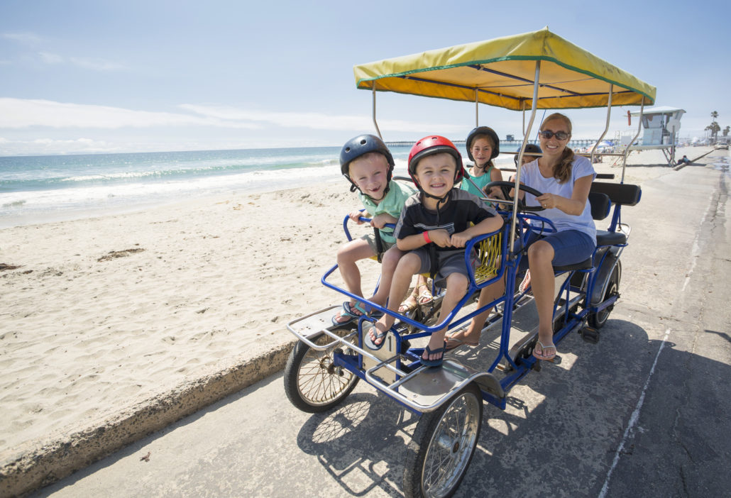 Family bike ride on beach boardwalk in California
