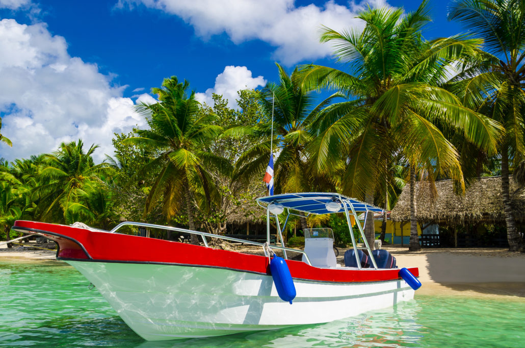 Blue, white, red boat on azure water among palm trees