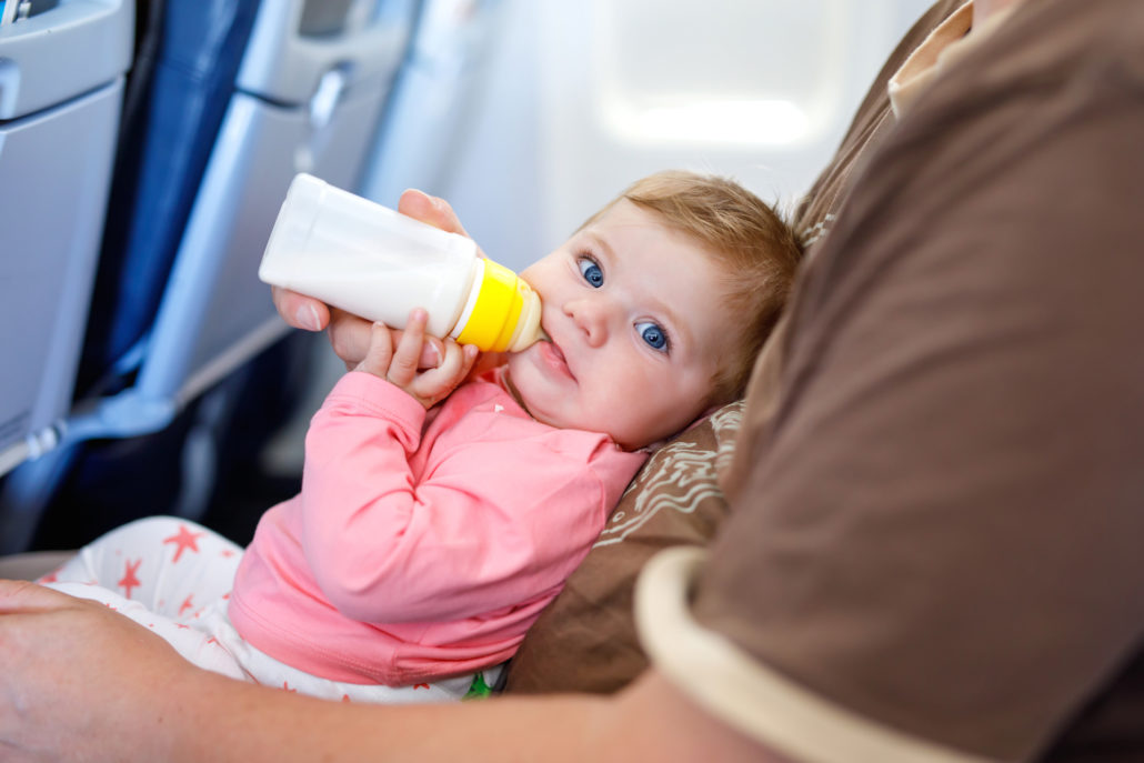 Father holding his baby daughter during flight on airplane going on vacations