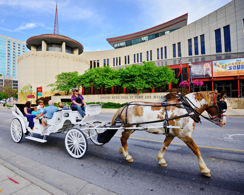 Tourists in a horse-drawn carriage pass the Country Music Hall of Fame and Museum. 