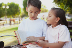 Kids reading outside together. Photo: Oleksandra Polishchuk | Dreamstime.com
